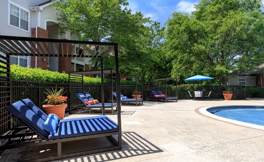 A poolside patio with a blue lounge chair and a pool.
