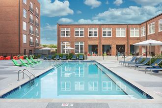 a swimming pool with lounge chairs in front of a building