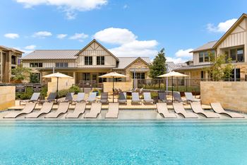 a swimming pool with lounge chairs in front of a house