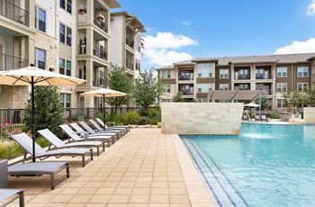 a swimming pool with lounge chairs next to an apartment building