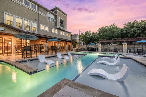 A large outdoor pool area with lounge chairs and umbrellas.