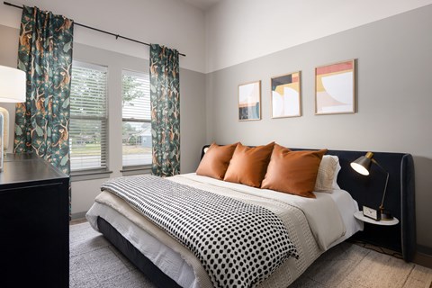 A bedroom with a bed, pillows, and pictures on the wall.