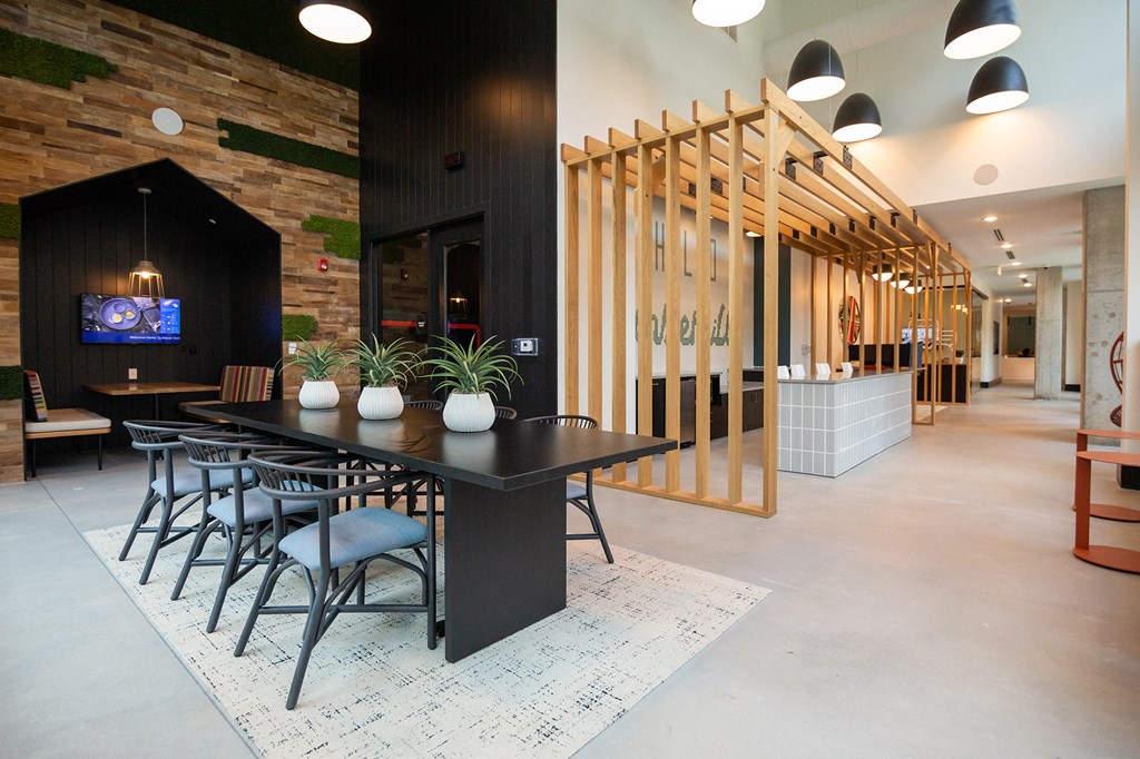 a large dining room with a black table and chairs and a tv on the wall