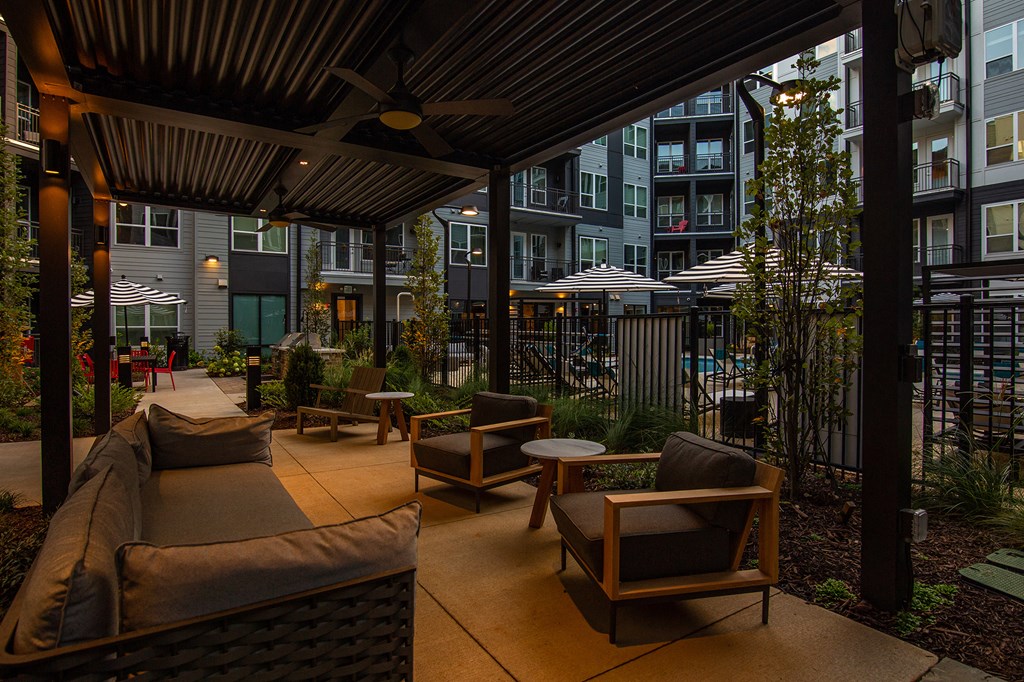 a patio with a couch and chairs and tables in front of an apartment building