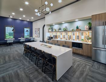 A modern kitchen with a long white island and dark wood flooring.