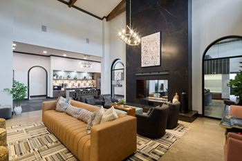 A living room with a brown sofa and a chandelier.