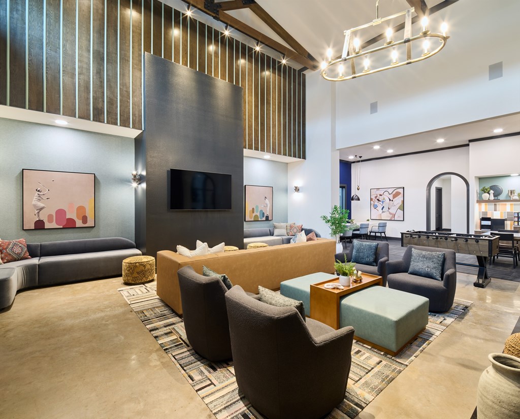 A modern living room with a variety of seating options and a flat screen TV mounted on the wall.