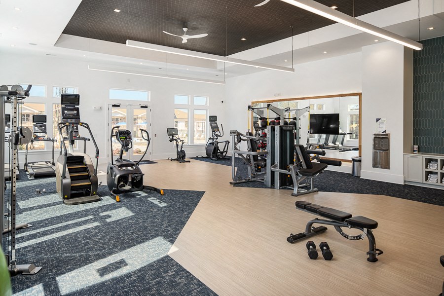 a gym with treadmills and other exercise equipment in a building with windows