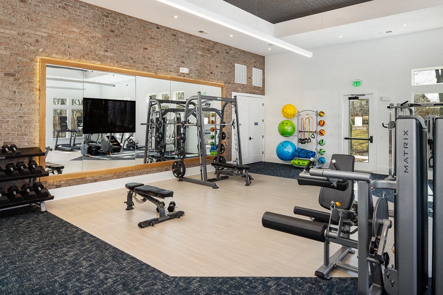 a gym with weights and cardio equipment and a large window