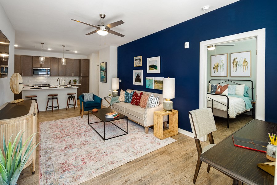 a living room with a blue accent wall and a kitchen