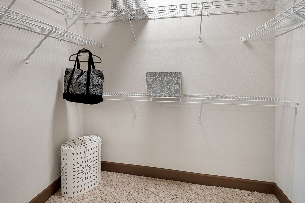 a walk in closet with a basket and bags hanging on a rack