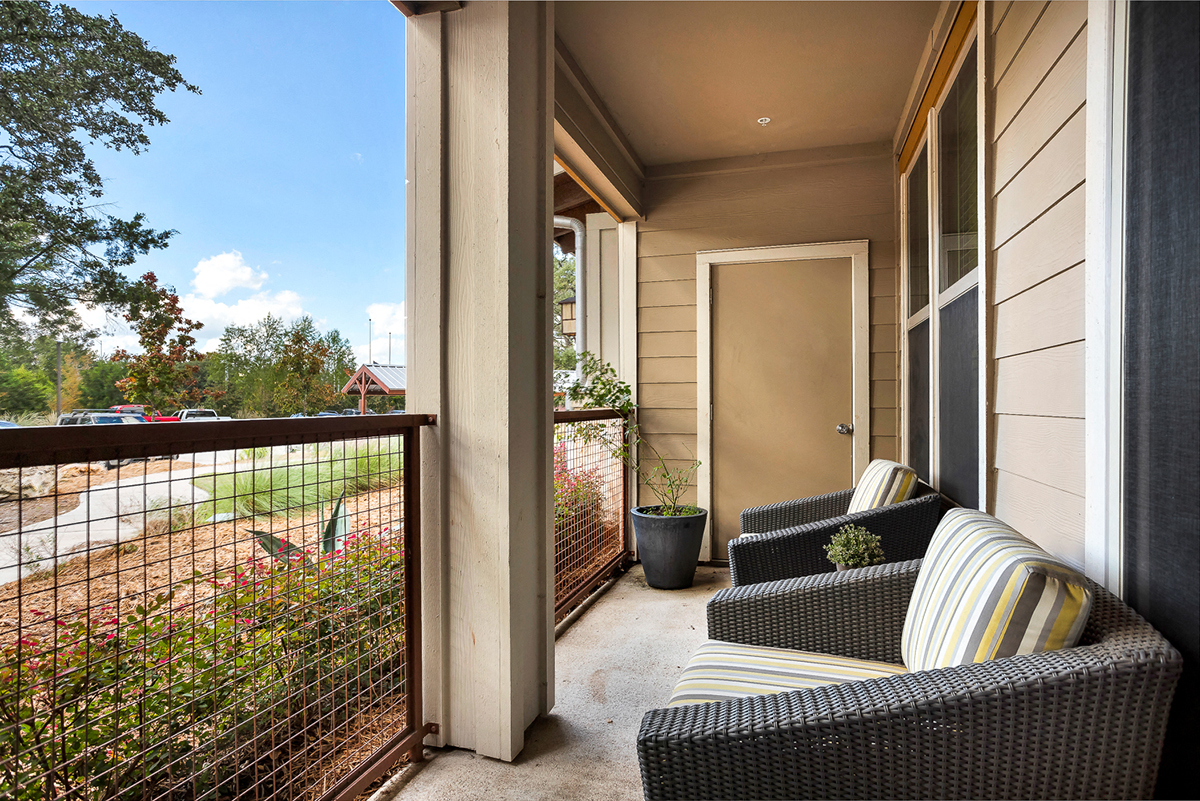 a balcony with two couches and a fence and a door to a house