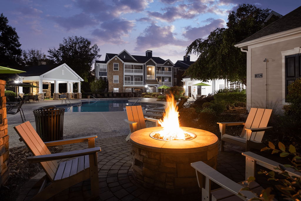 a fire pit in the middle of a backyard with a swimming pool