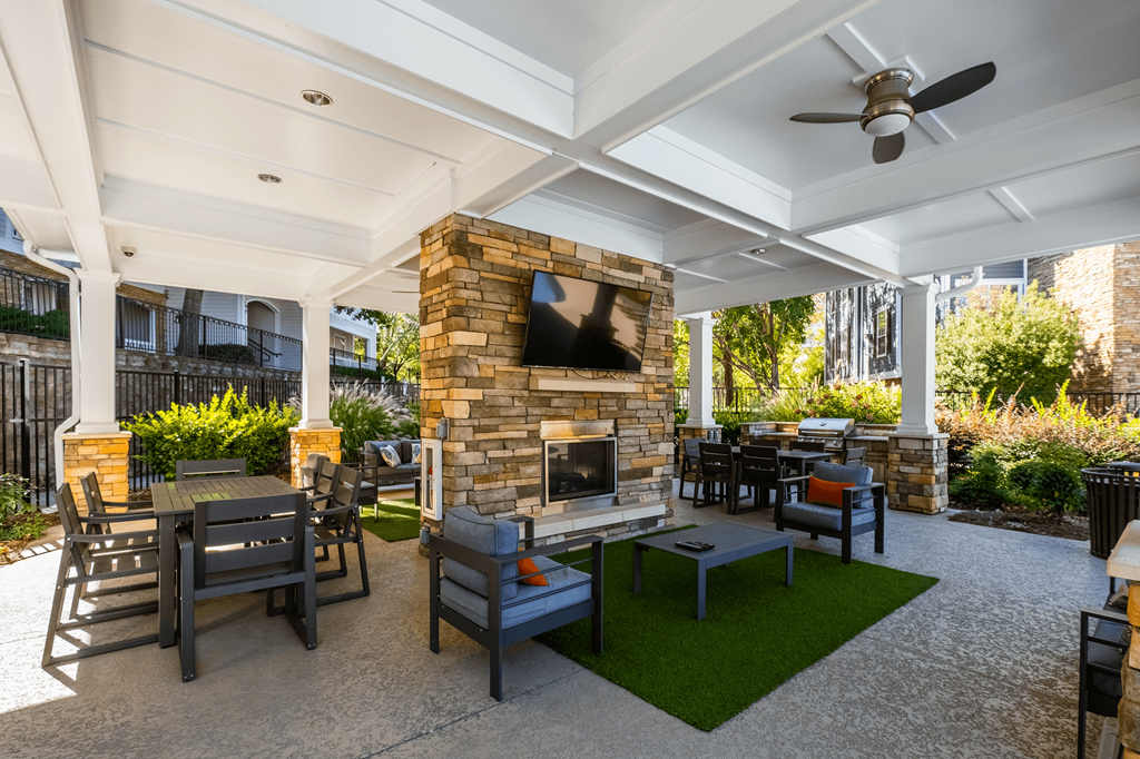 a patio with a stone fireplace and tables and chairs
