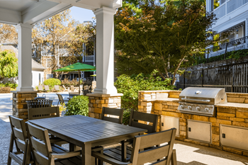 a patio with a table and chairs and a grill
