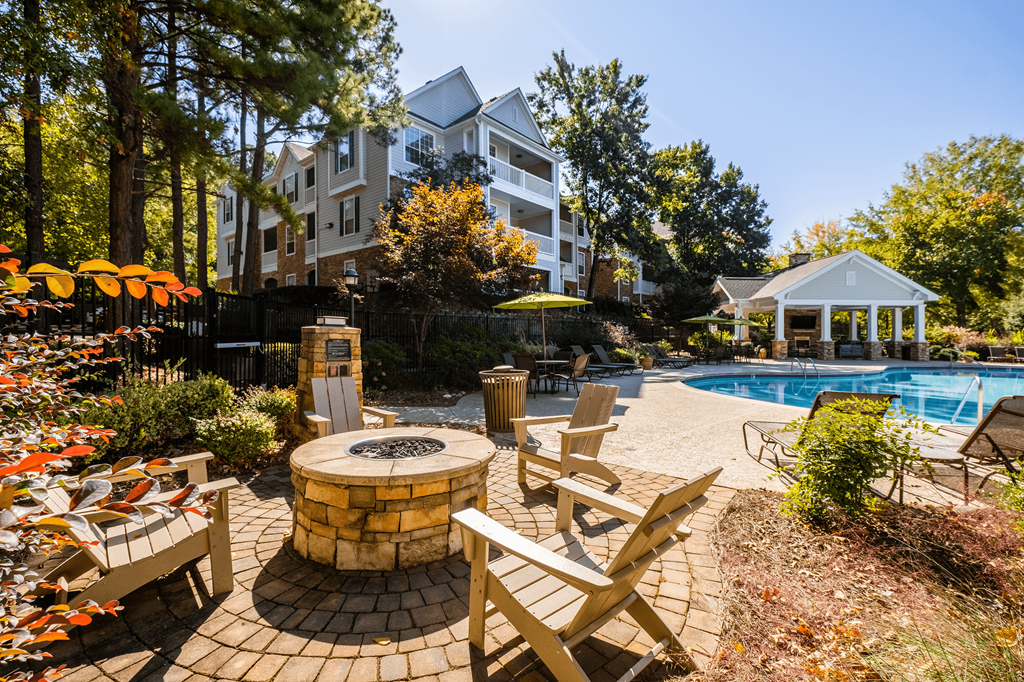 a backyard with a pool and patio with chairs and umbrellas