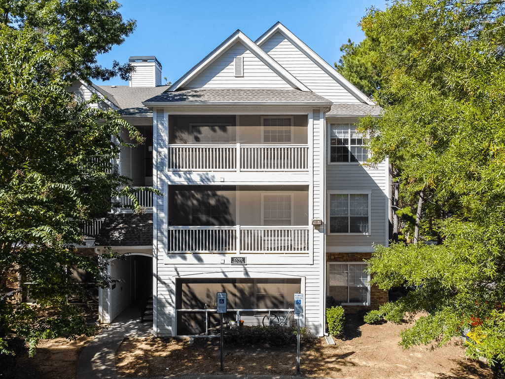 the view of a white house with trees in front of it