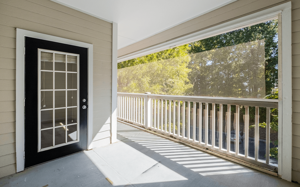 the front porch of a home with a black door and white railing