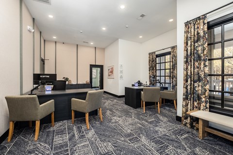 A reception area with a desk, chairs, and a large window with curtains.