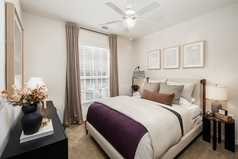 A bedroom with a large bed and a ceiling fan.