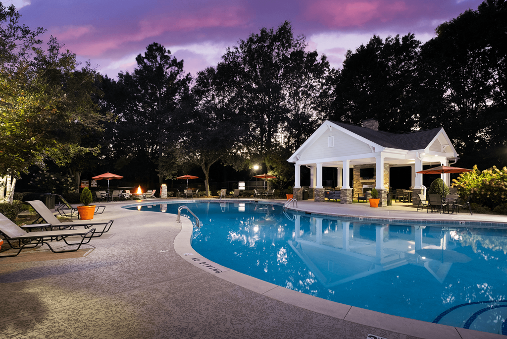 a swimming pool at night in front of a house