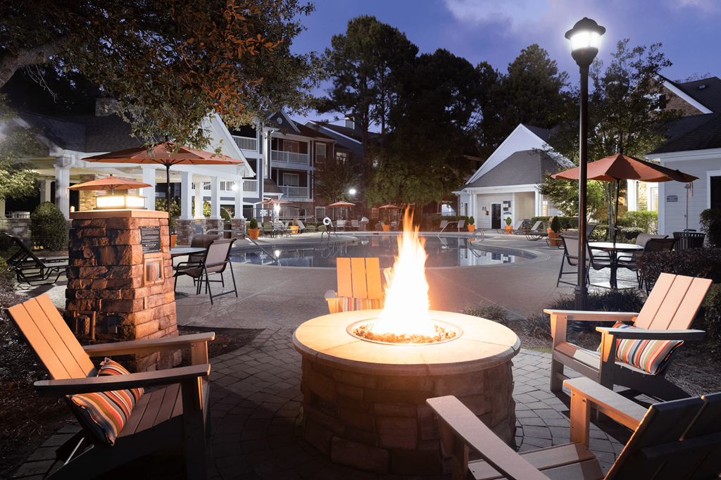 a fire pit in front of a swimming pool at night