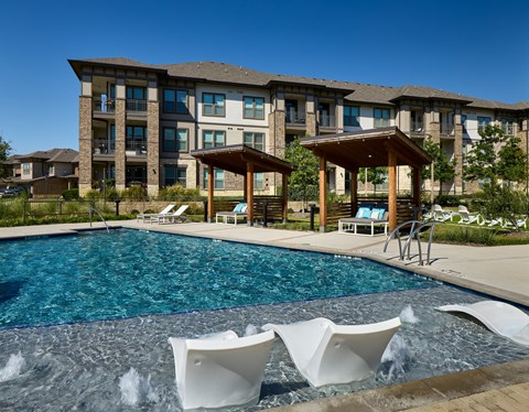 A large swimming pool in front of a building with a gazebo.