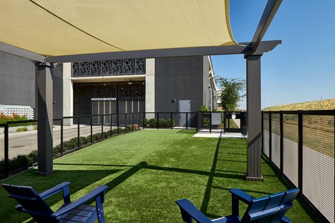 A sunny day at the park with blue chairs and a yellow canopy.