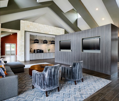 A modern living room with grey chairs and a stone wall.