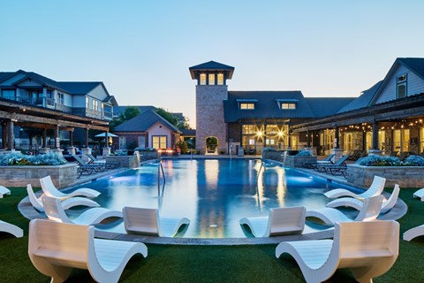 A large white pool surrounded by chairs in front of a house.