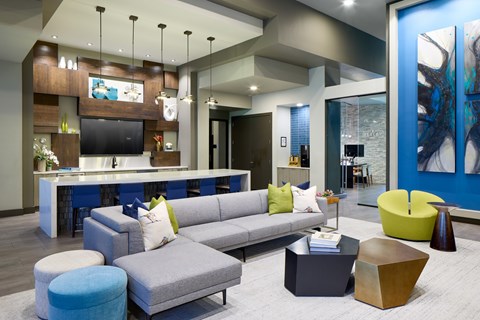 A modern living room with a grey sofa and a blue ottoman.