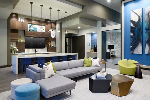 A modern living room with a grey sofa and a blue ottoman.