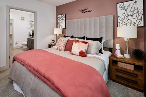 A bedroom with a bed, nightstand, and lamp.