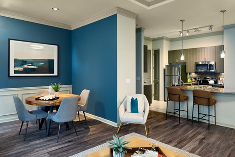 A modern kitchen with blue walls and a dining table set for four.