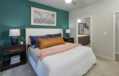 A bedroom with a bed, nightstands, and a painting on the wall.