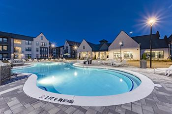 a swimming pool at night with a building in the background
