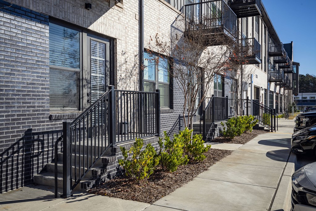 front view of a brick apartment building with stairs and a sidewalk