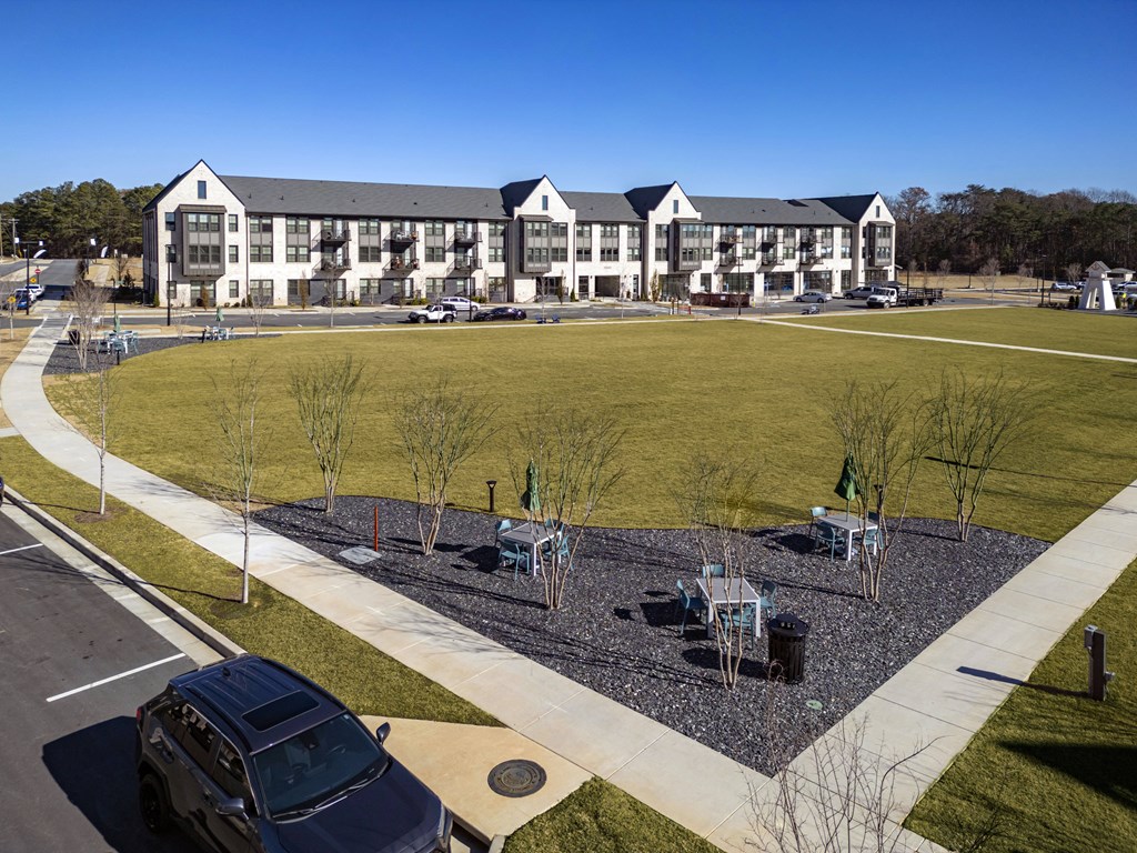 an aerial view of an apartment building with a field and a parking lot