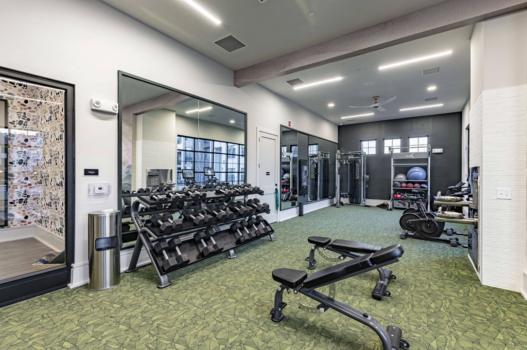a gym with weights and mirrors and a glass door