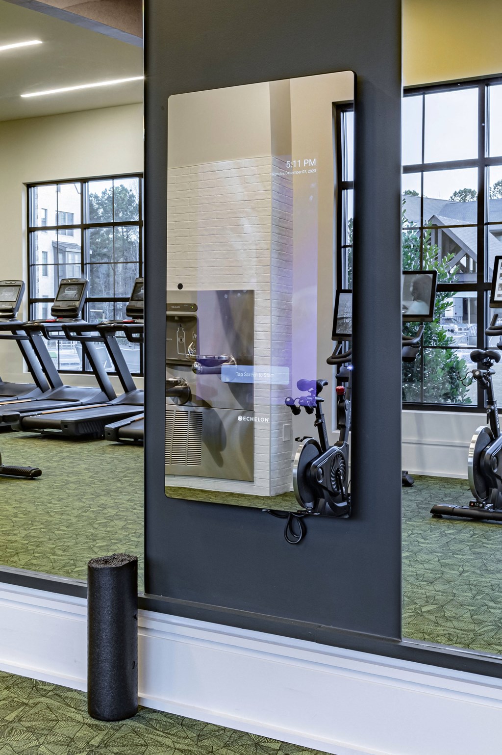 a glass wall with a reflection of a gym mirror in a gym with exercise equipment