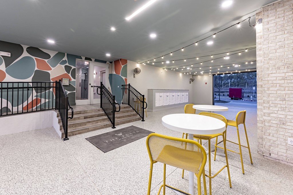 a lobby with yellow chairs and tables and a staircase