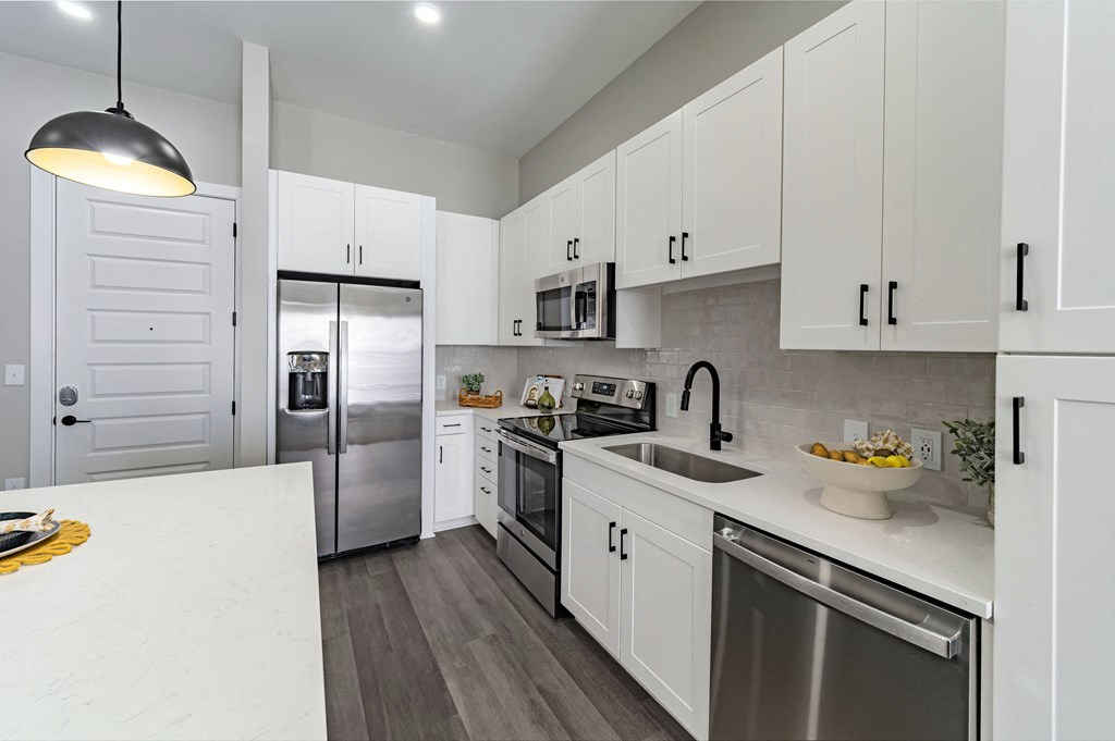 a large kitchen with white cabinets and stainless steel appliances