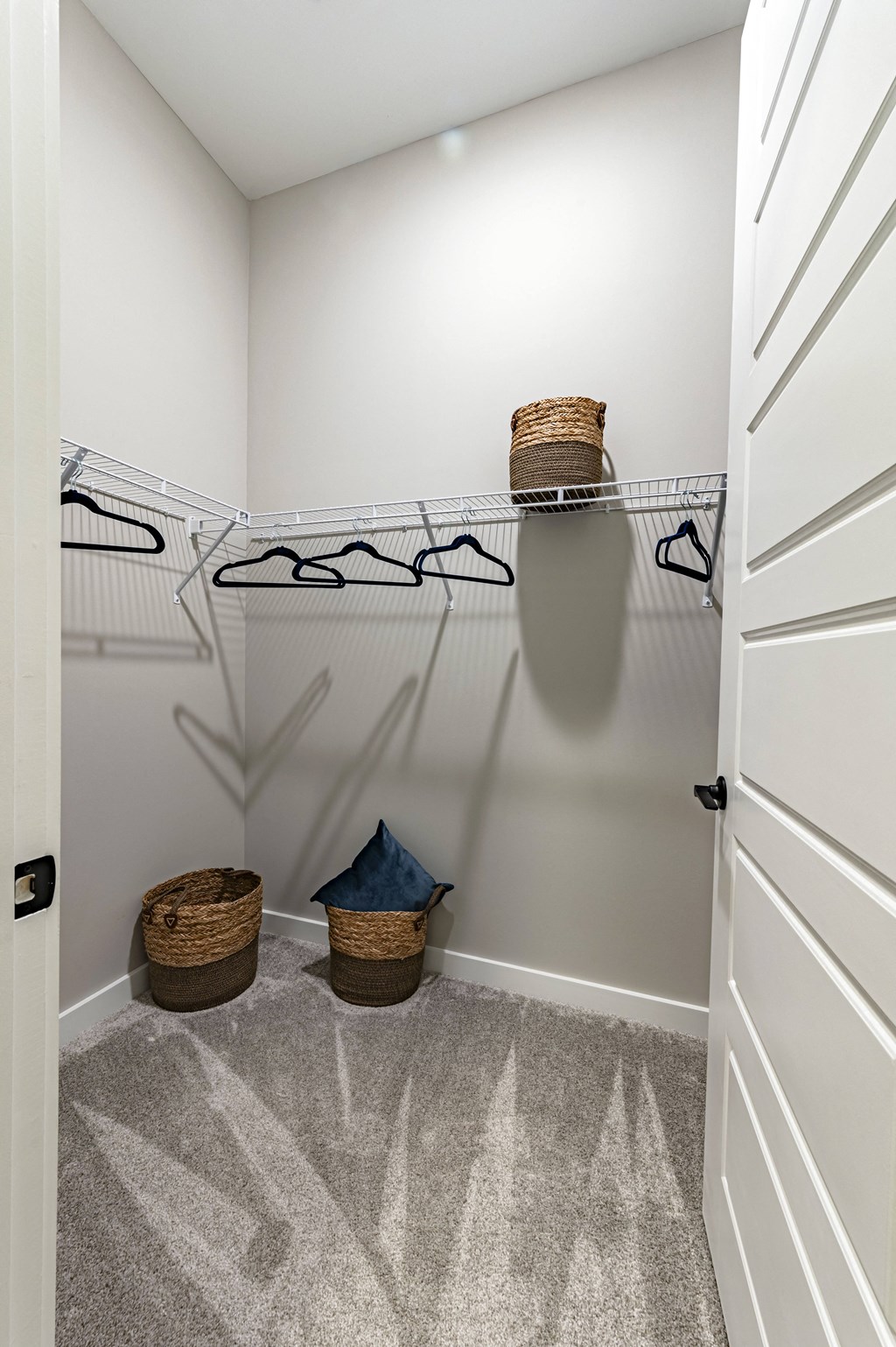 the walk in closet in a new home with white walls and carpet