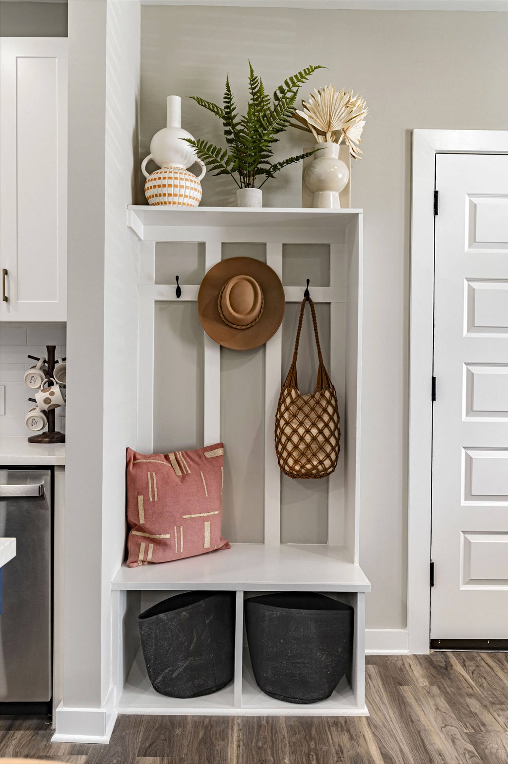 a white shelf with baskets and a hat and a purse on it