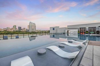 a rooftop pool with lounge chairs and a view of the city