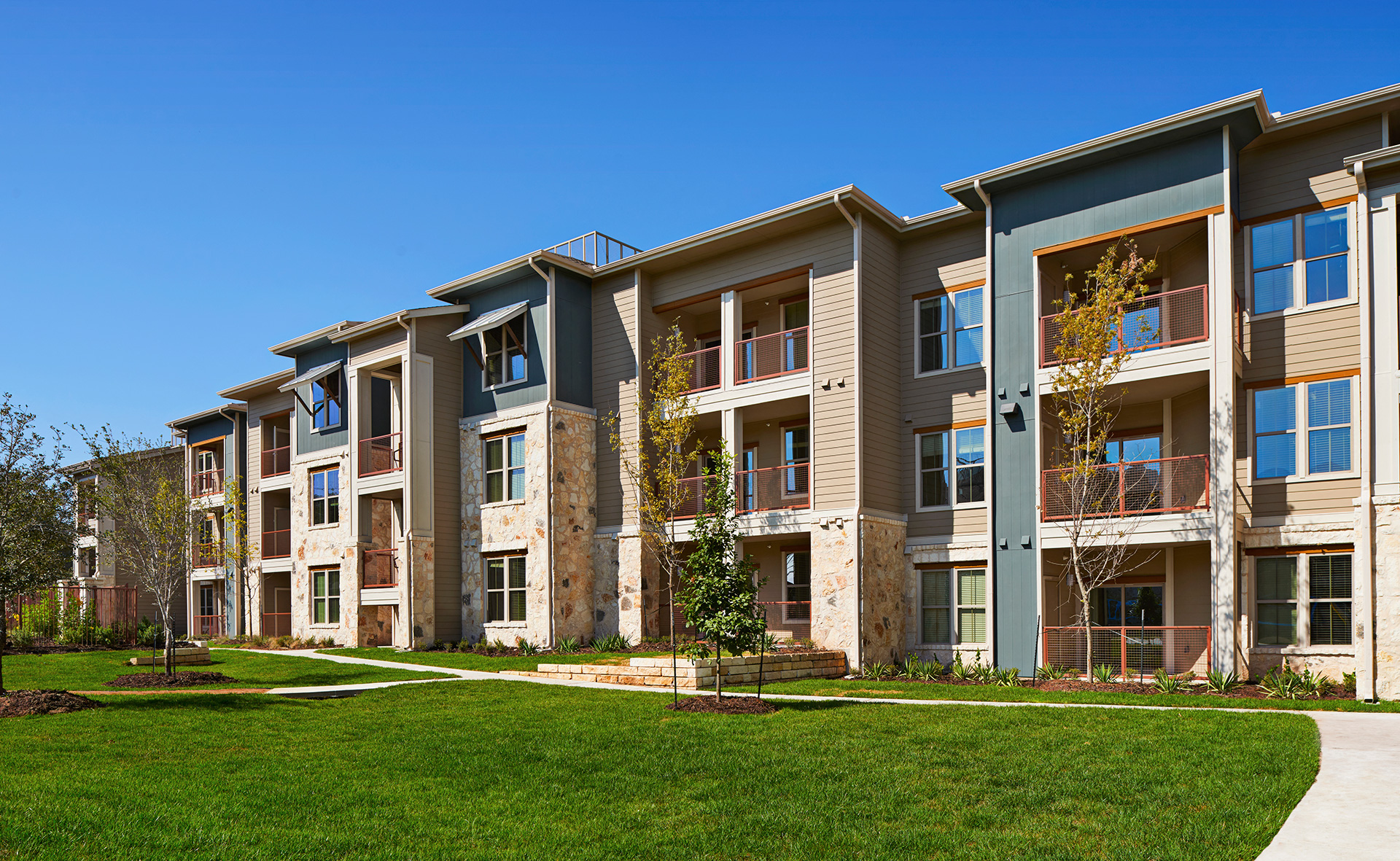 an apartment building with green grass in front of it