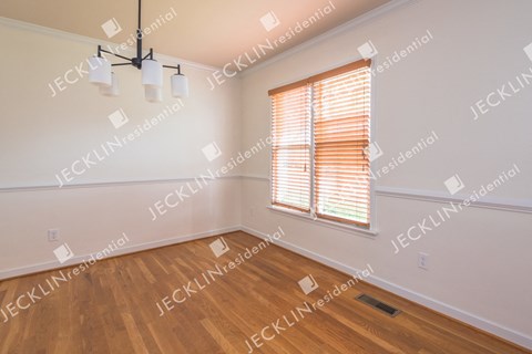 A room with wooden floors and a window with blinds.