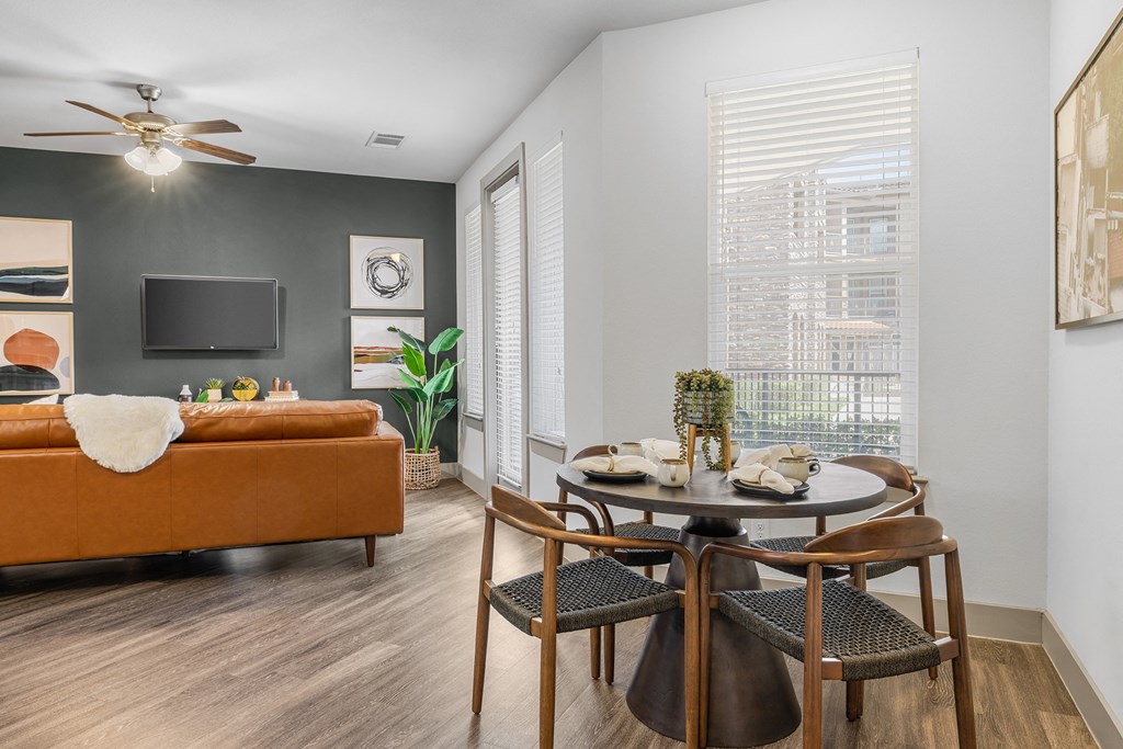 a dining area with a round table and four chairs and a couch in the background