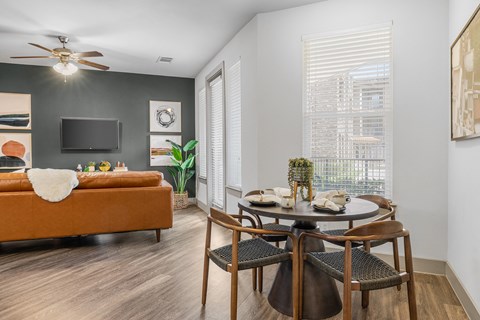 a dining area with a round table and four chairs and a couch in the background