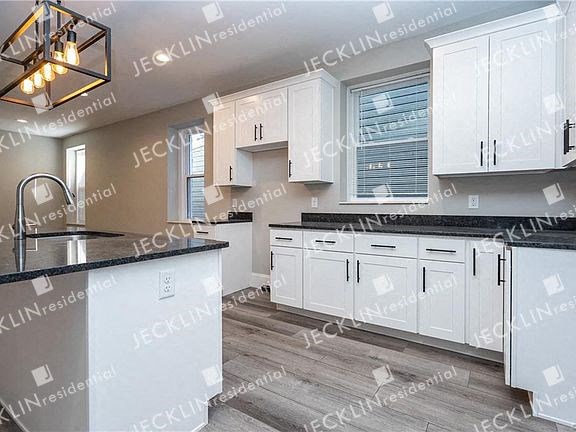 a kitchen with white cabinets and black counter tops